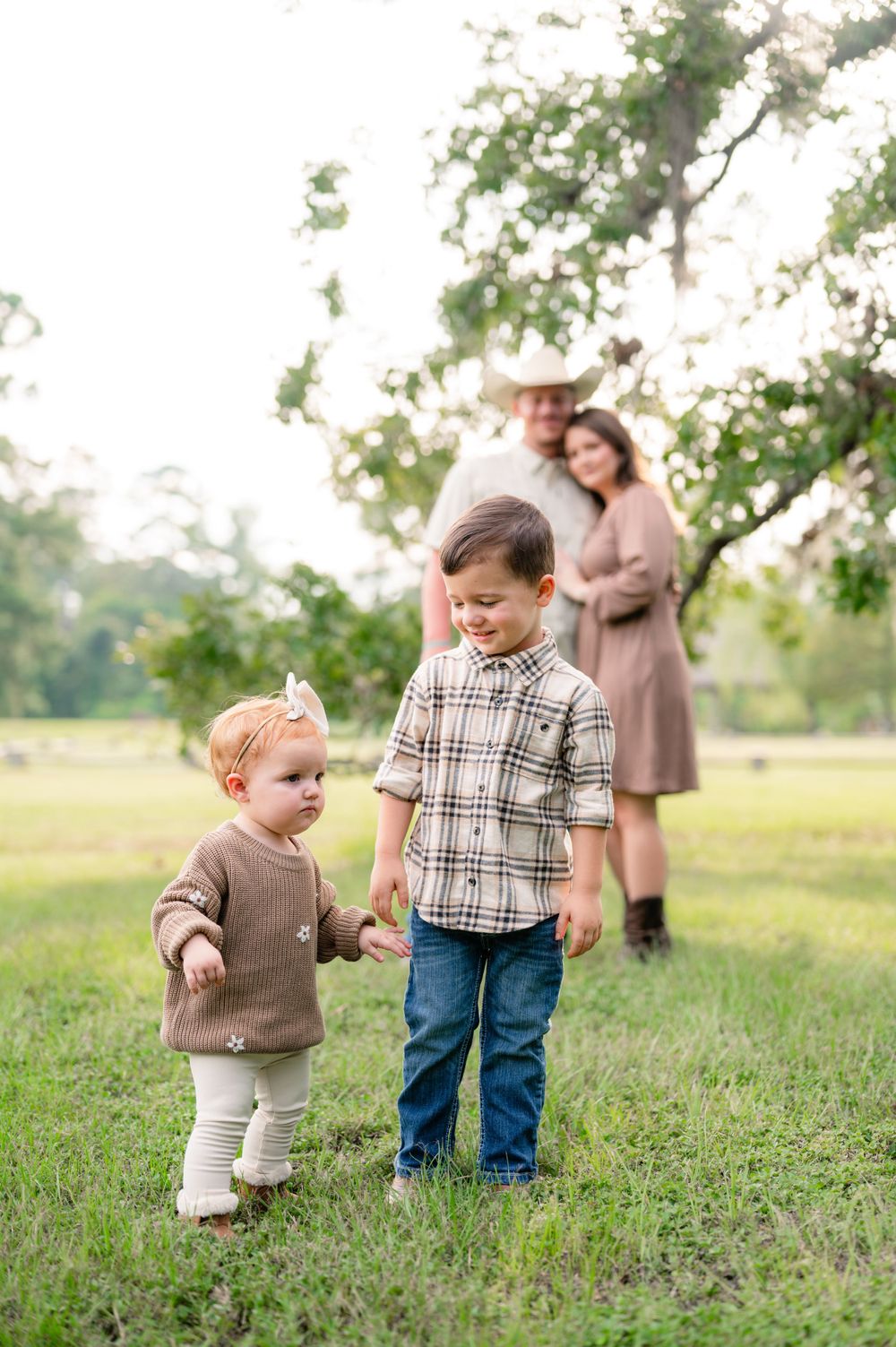 Young children playing outdoors while being watched by an adult in the background.