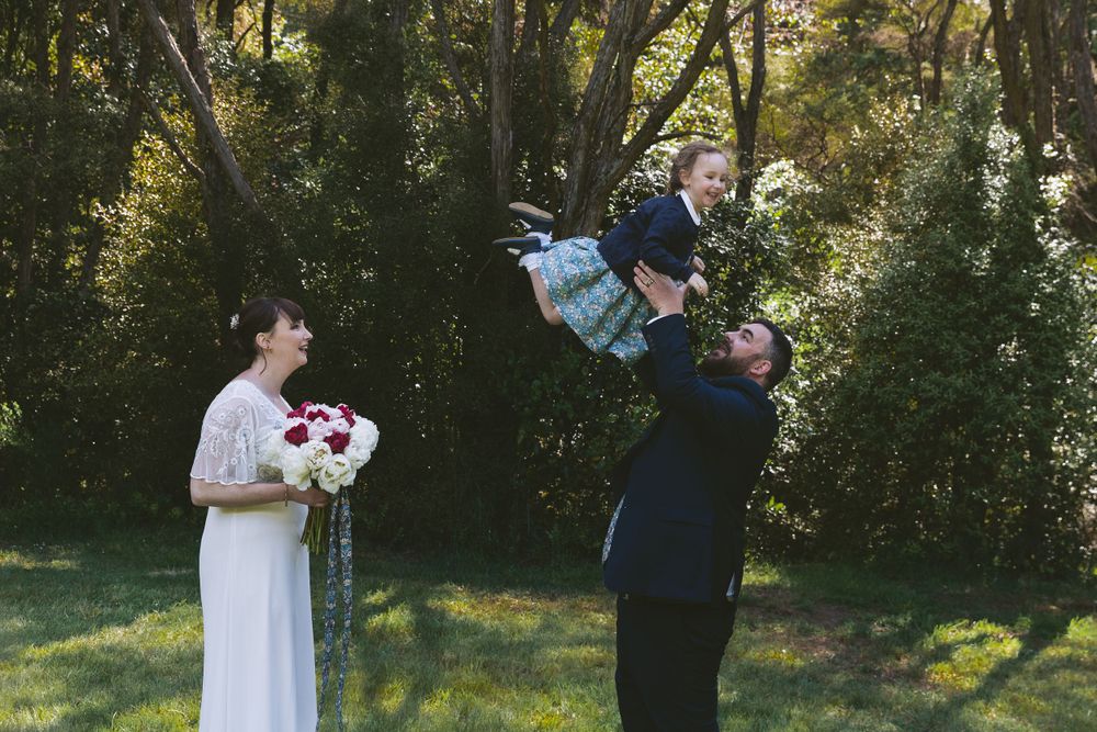 Joyful moment at outdoor wedding with bouquet and playful interactions.