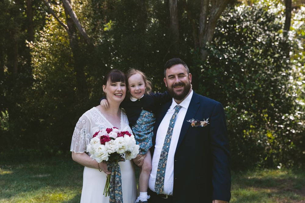 Wedding portrait on grass with trees and natural lighting in background.