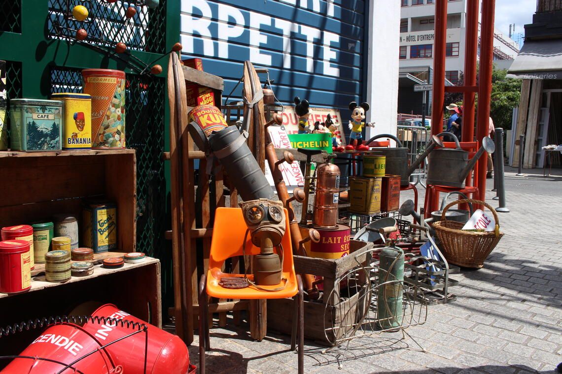 Vintage antique shop display with bottles and collectibles on outdoor shelves in a European street setting.