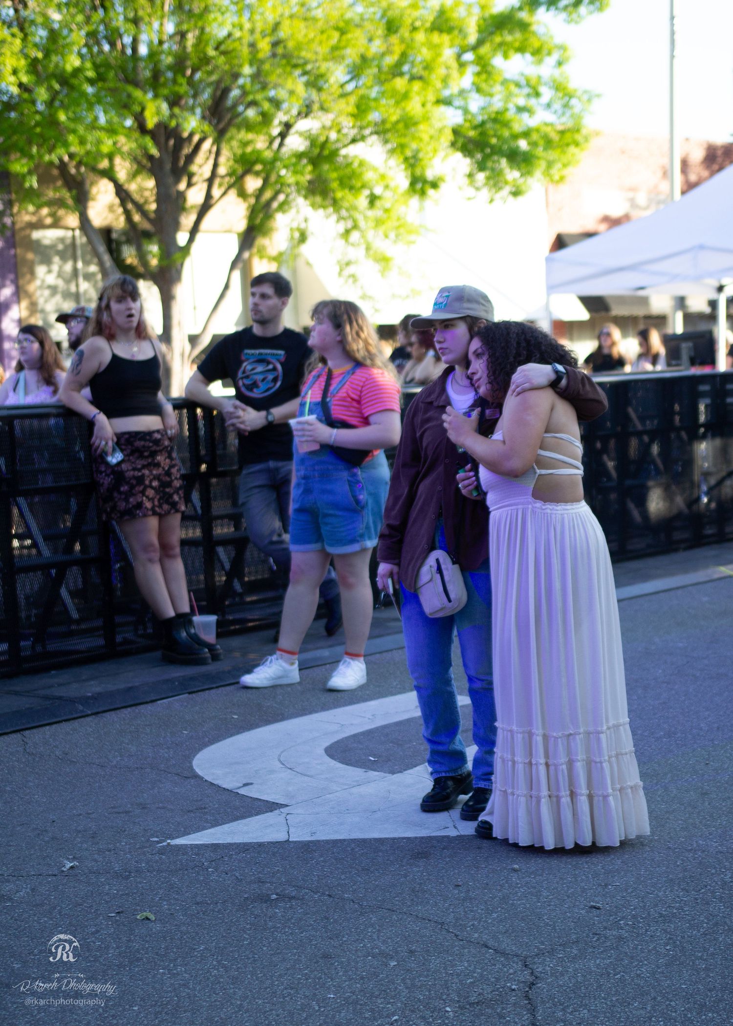 Festival attendees lined up along a barrier watching a performance during an outdoor event.