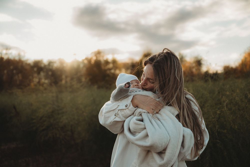 Gentle moment between parent and baby photographed in warm evening light.