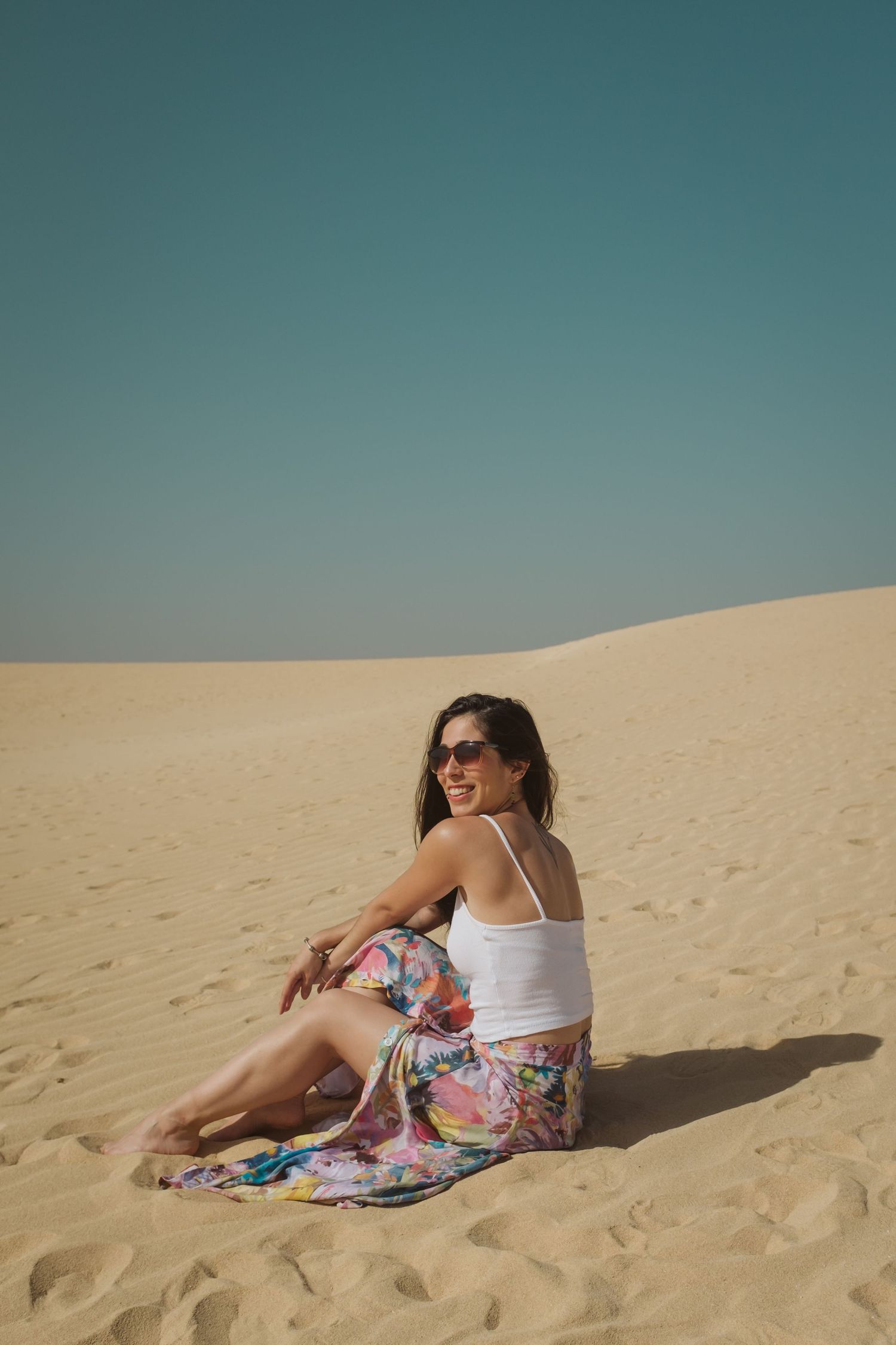 lifestyle portrait photography of women smiling and happily sitting in a sandy beach