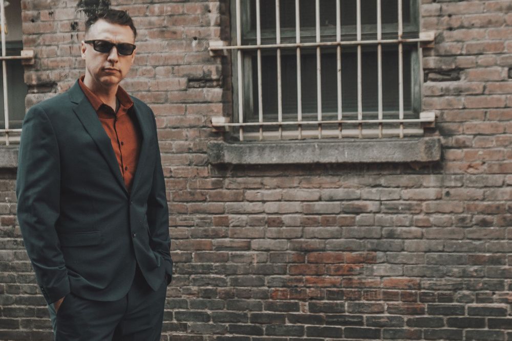 Urban fashion portrait with sunglasses against industrial brick wall background.