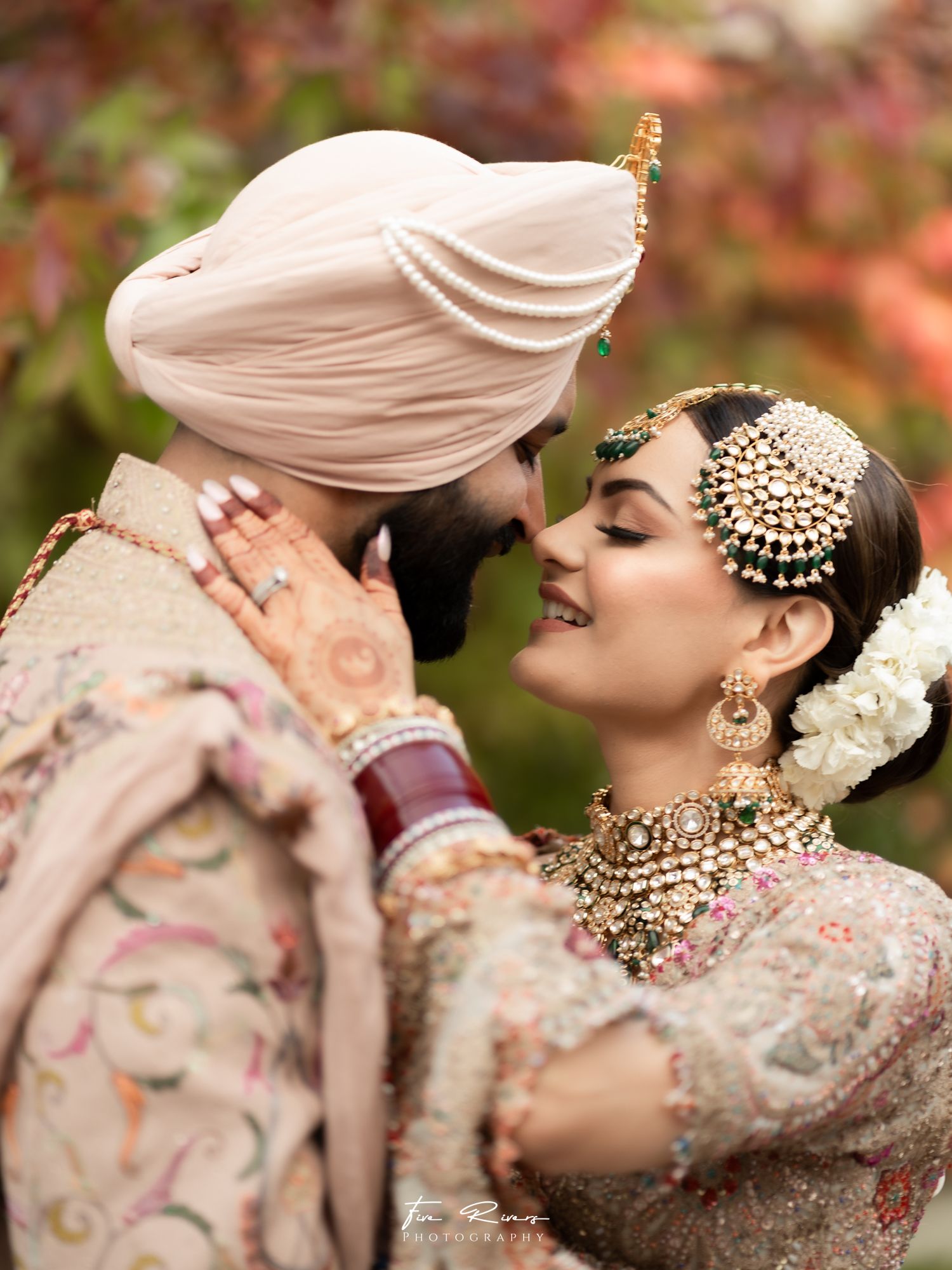 A romantic moment between a couple in traditional South Asian wedding attire with ornate jewelry and henna designs.