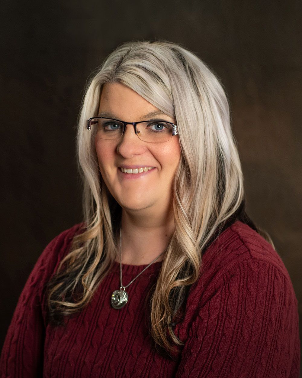 corporate headshot of a woman in burgundy top on a dark background backlighting by professional photographer Luba wold in Post Falls Idaho