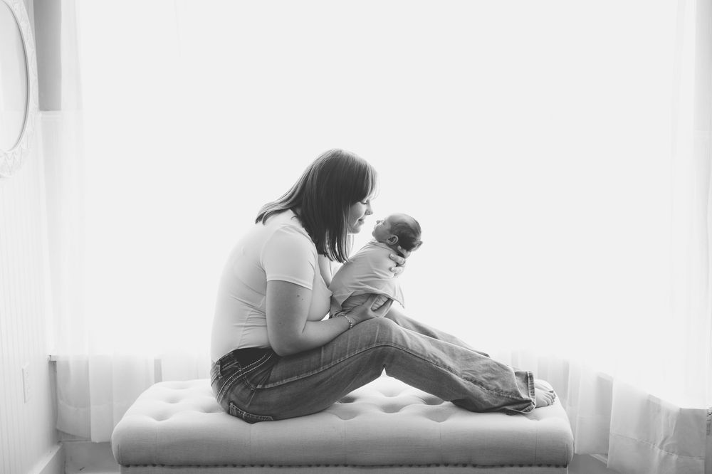 A series of black and white photographs showing tender nurturing moments between parent and baby in a soft natural light.