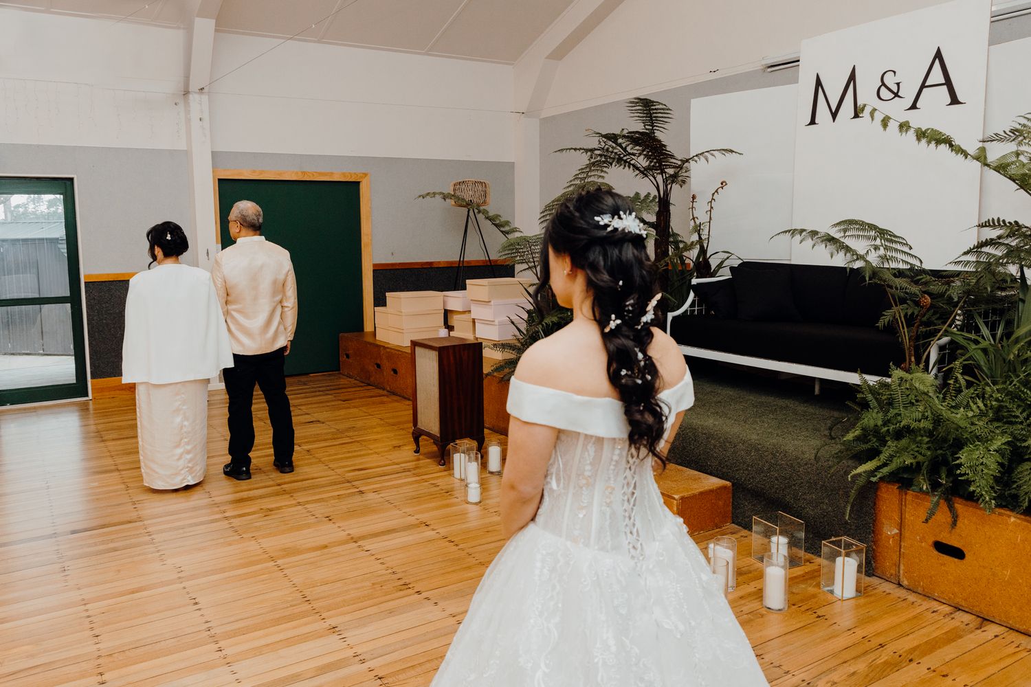 Wedding venue showing piano, candles, and decorative plants with hardwood floors.