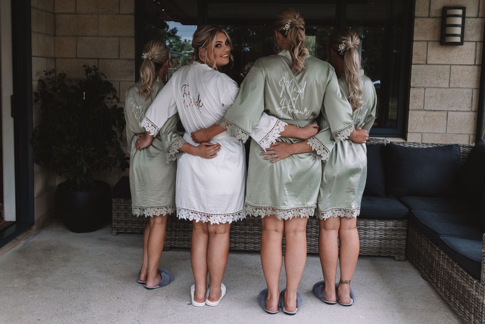 Four people in matching robes showing backs to camera while standing together.