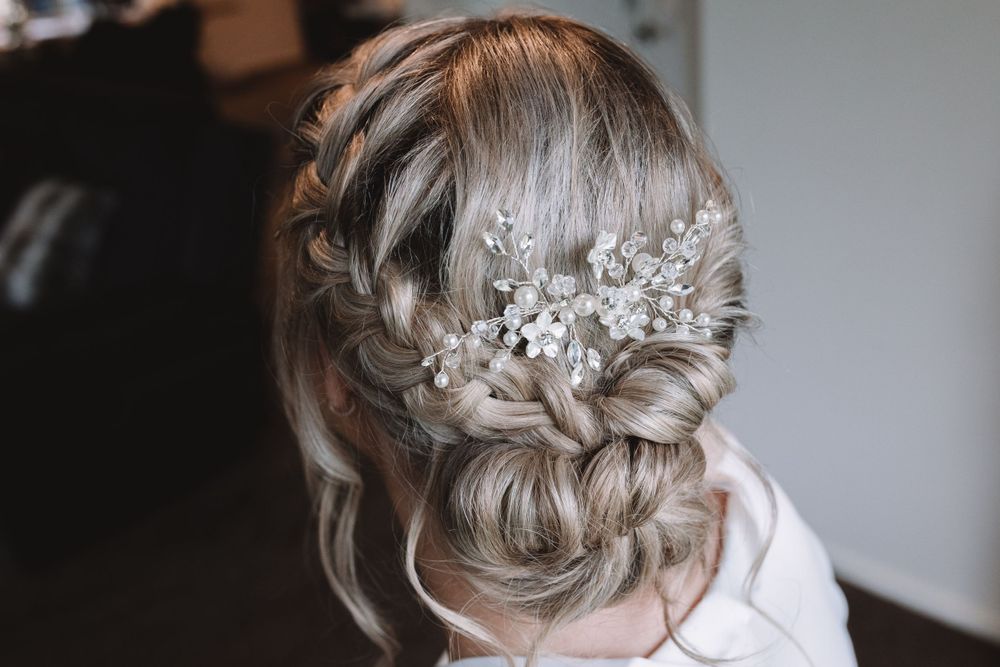 Elegant bridal hairstyle featuring braids, pearls and floral accessories in an updo.