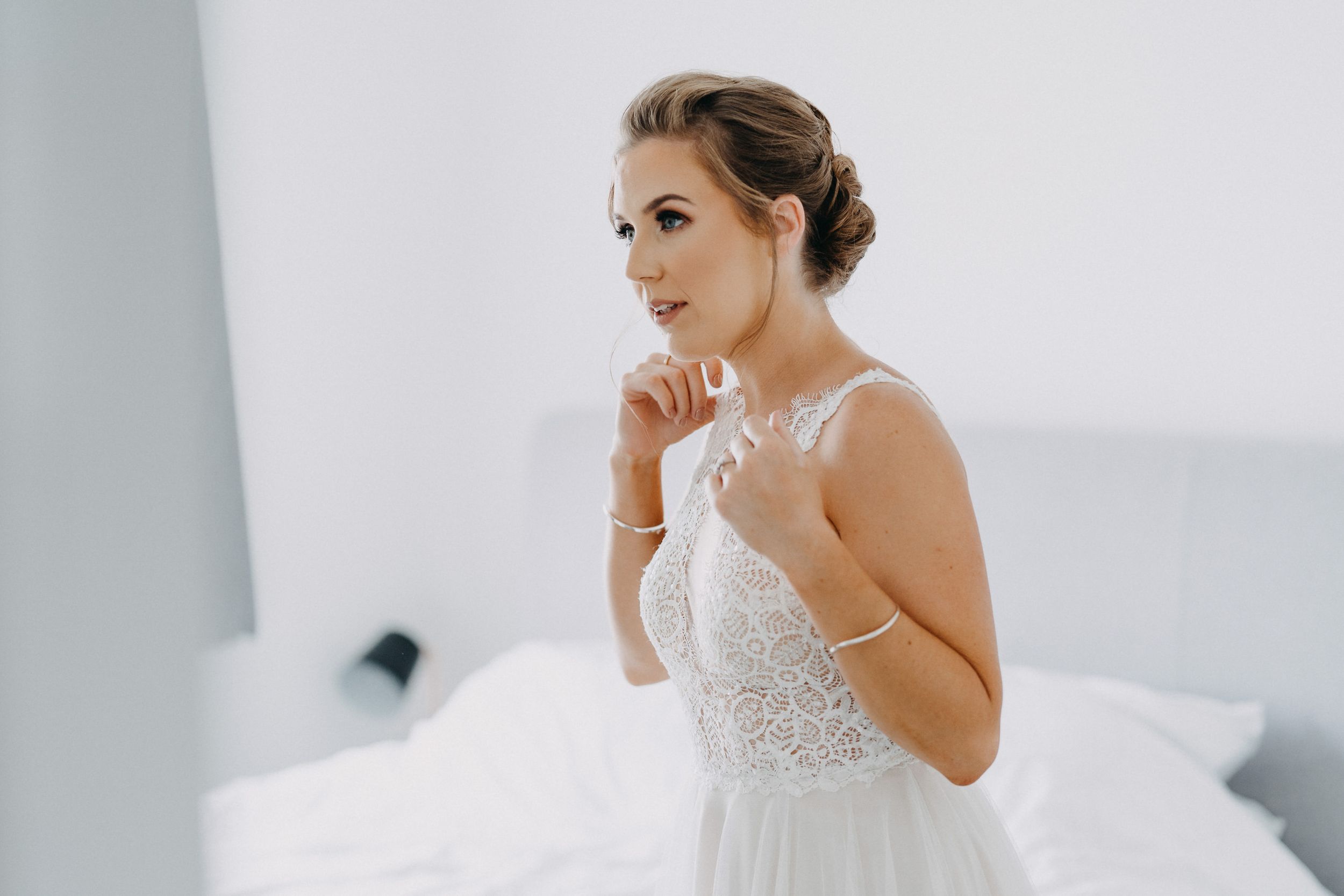 Elegant white wedding gown with delicate lace bodice and flowing tulle skirt photographed against light background.