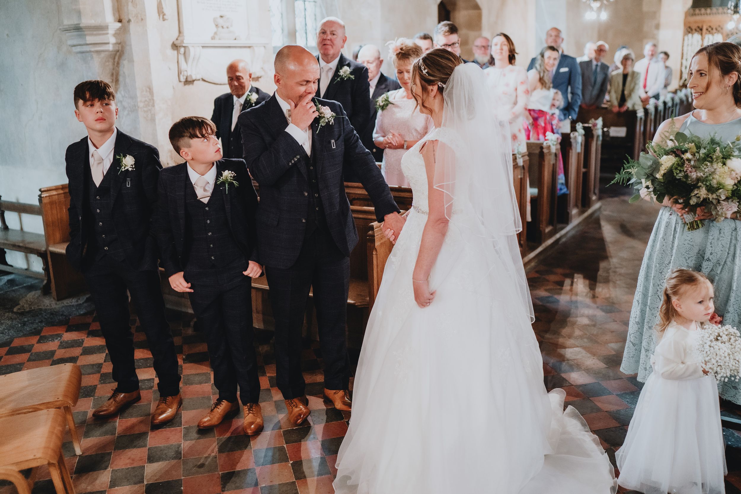 A traditional church wedding ceremony in progress with attendees in formal attire and elegant floral decorations.