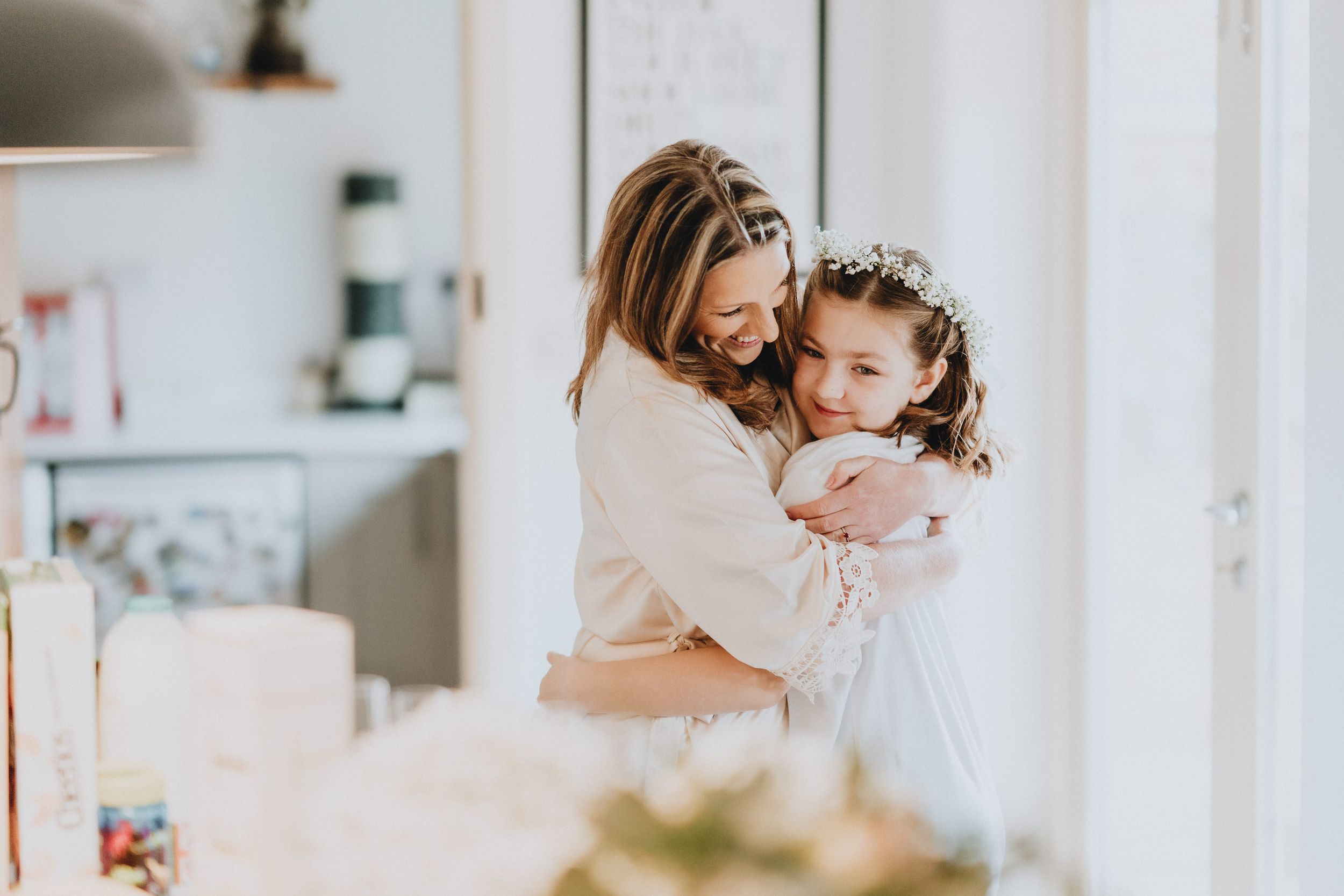 A tender embrace between parent and child in a bright, airy room with soft natural lighting.