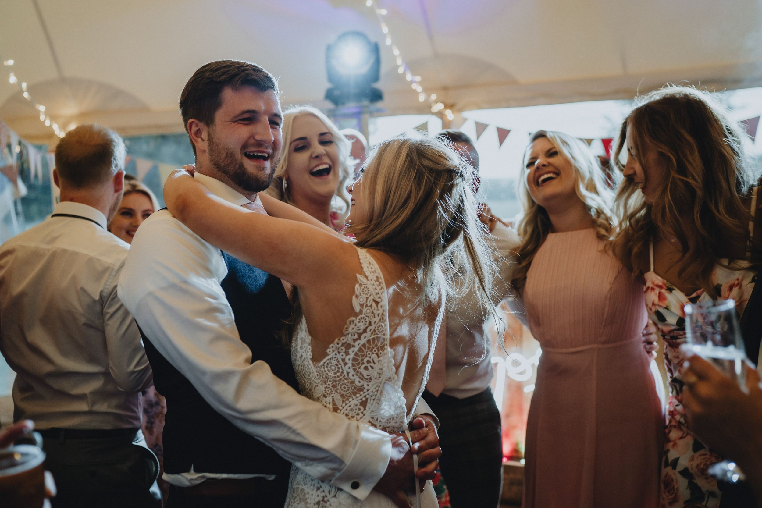 A joyful celebration of guests dancing and laughing together at a wedding reception.