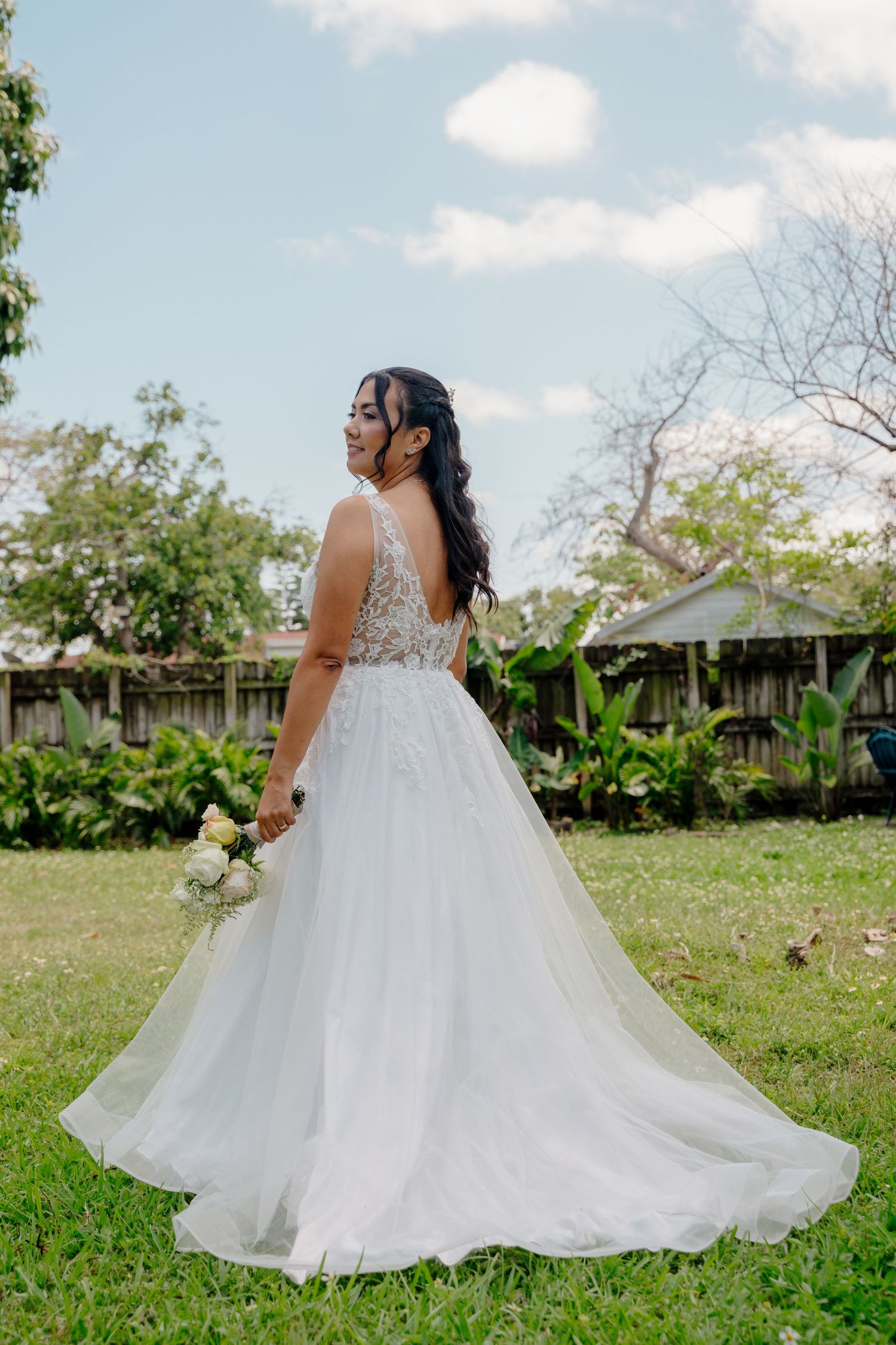 A bride in a flowing white ballgown twirls gracefully in a sun-drenched garden setting, showcasing the dress's ethereal movement.