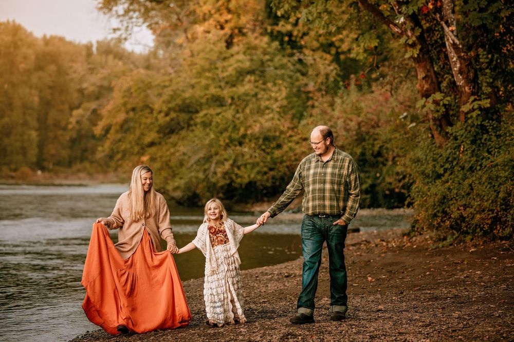 Family walking together on autumn path by river during fall season.