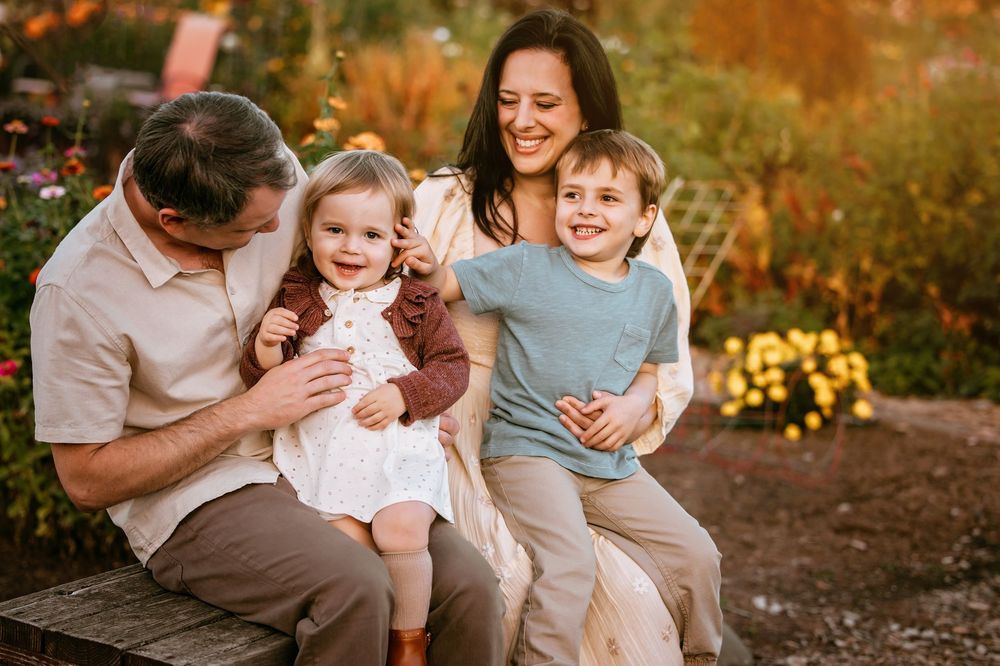Family sharing joyful moment together on wooden bench in garden at sunset.