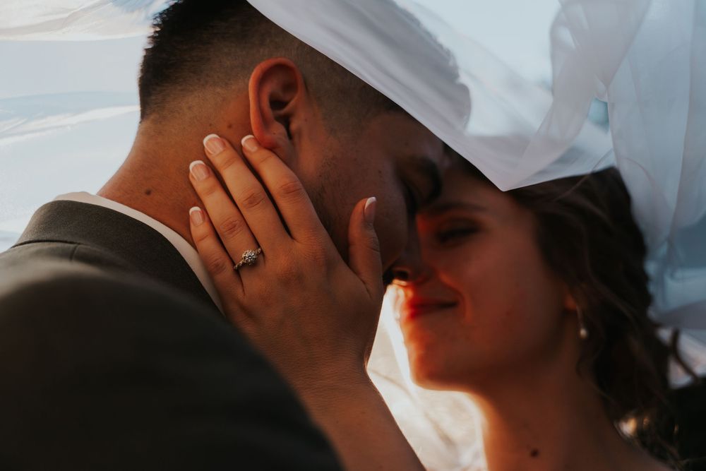 Romantic close-up photo of a bride and groom sharing an intimate moment under a veil.