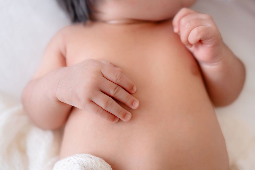 Close up view of a newborn baby's tiny hand resting on soft skin.