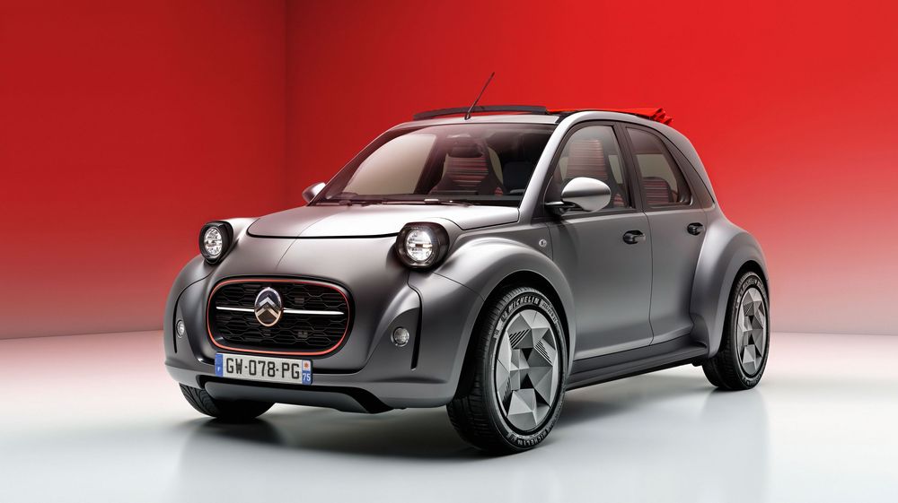 Sleek concept car showcasing a retro-modern design with silver paint and oversized wheels against a red gradient background.