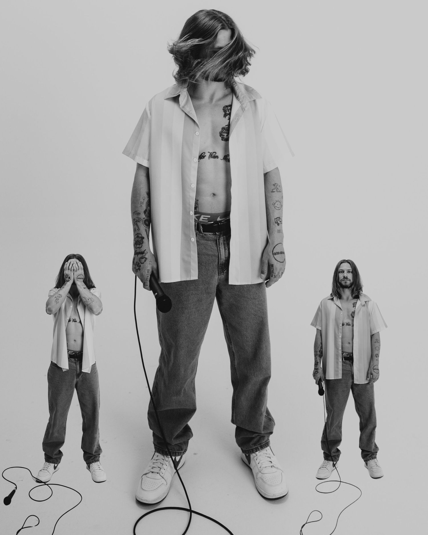 A black and white photo shows three people wearing loose t-shirts and jeans with a playful height variation styling.