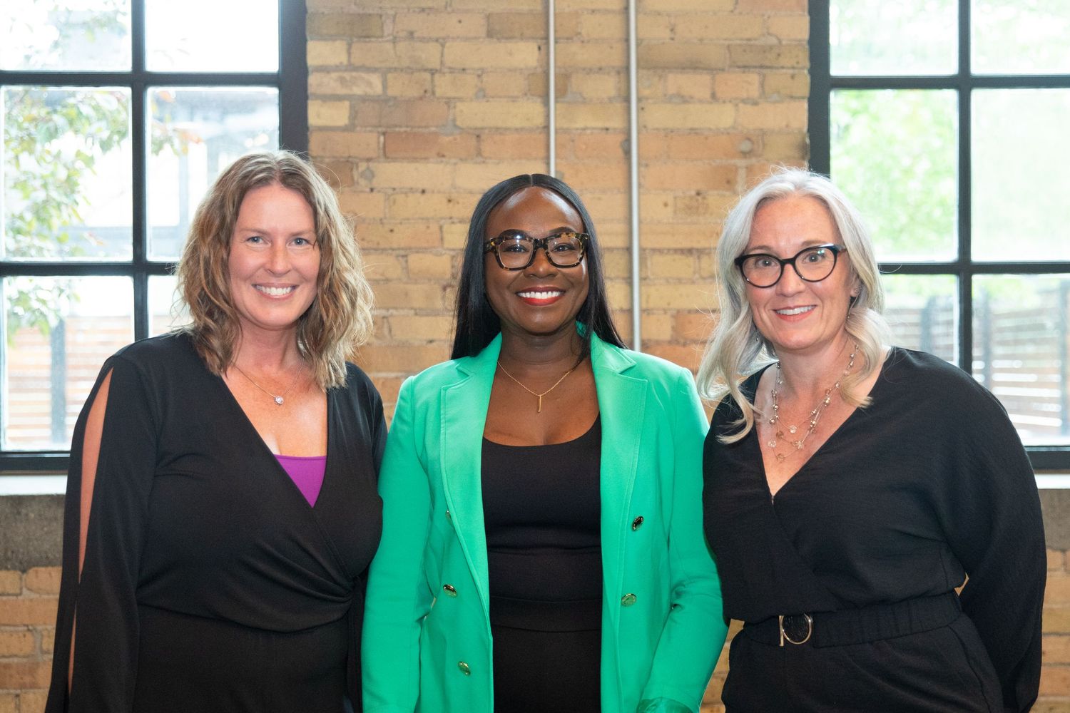 Three professionals posing together for a photo, with one wearing a vibrant green blazer in the middle.
