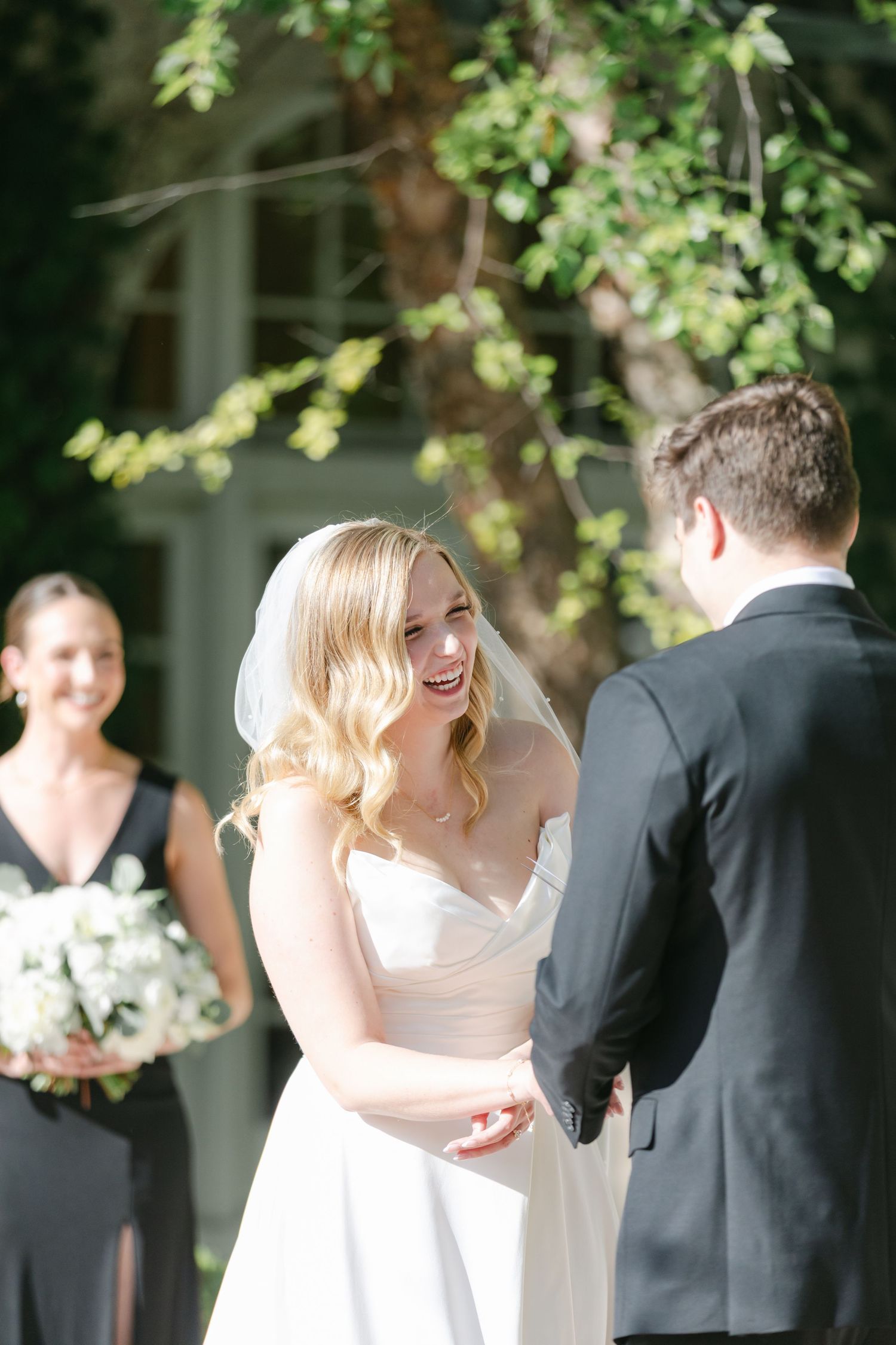 An outdoor garden wedding ceremony under a trellis with white floral decorations and formal attire.