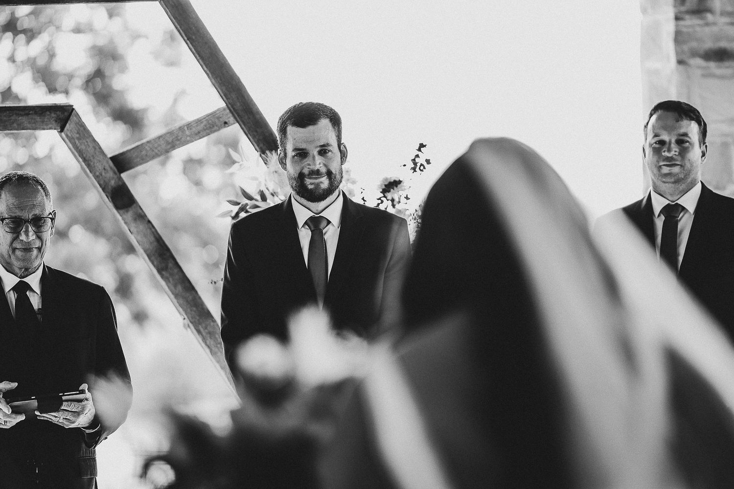 gorgeous black and white photo of the groom smiling at this bride with tears in his eyes as she walks down the aisle at their rustic wedding