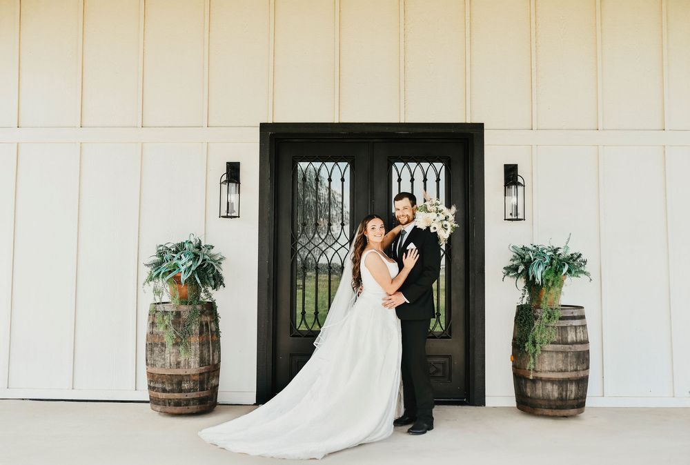 Bride and groom smiling in front of black barn doors at The Madelyn