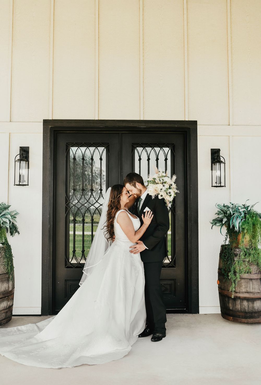 Formal wedding photo with bride and groom by black barn doors