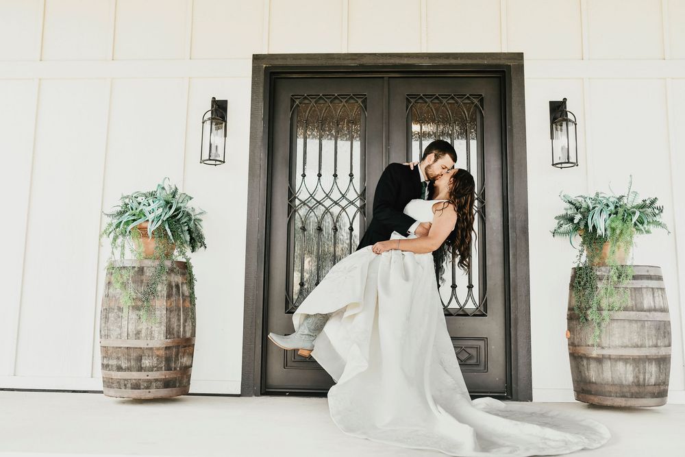 Bride and groom laughing in front of The Madelyn’s signature shiplap wall