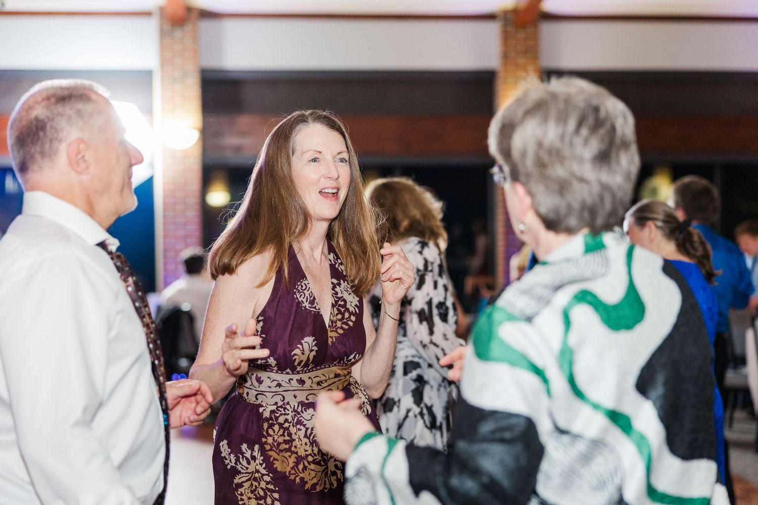Happy wedding guests dancing and celebrating on a festive dance floor during an evening reception.