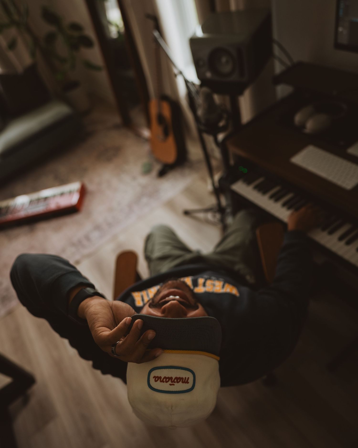 A pair of feet in black boots resting near music equipment with a guitar and keyboard visible in the background.