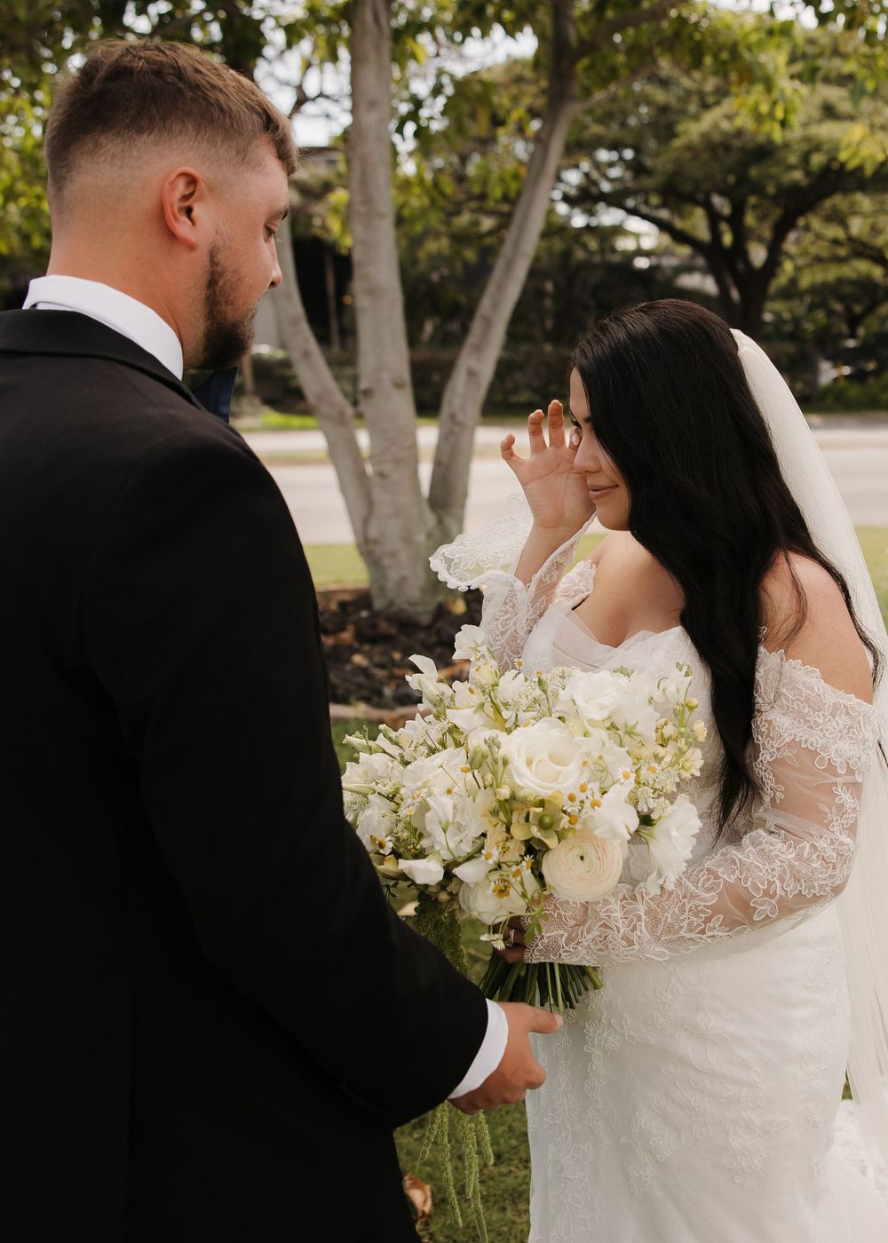 A wedding moment outdoors with lush greenery and white floral bouquet.
