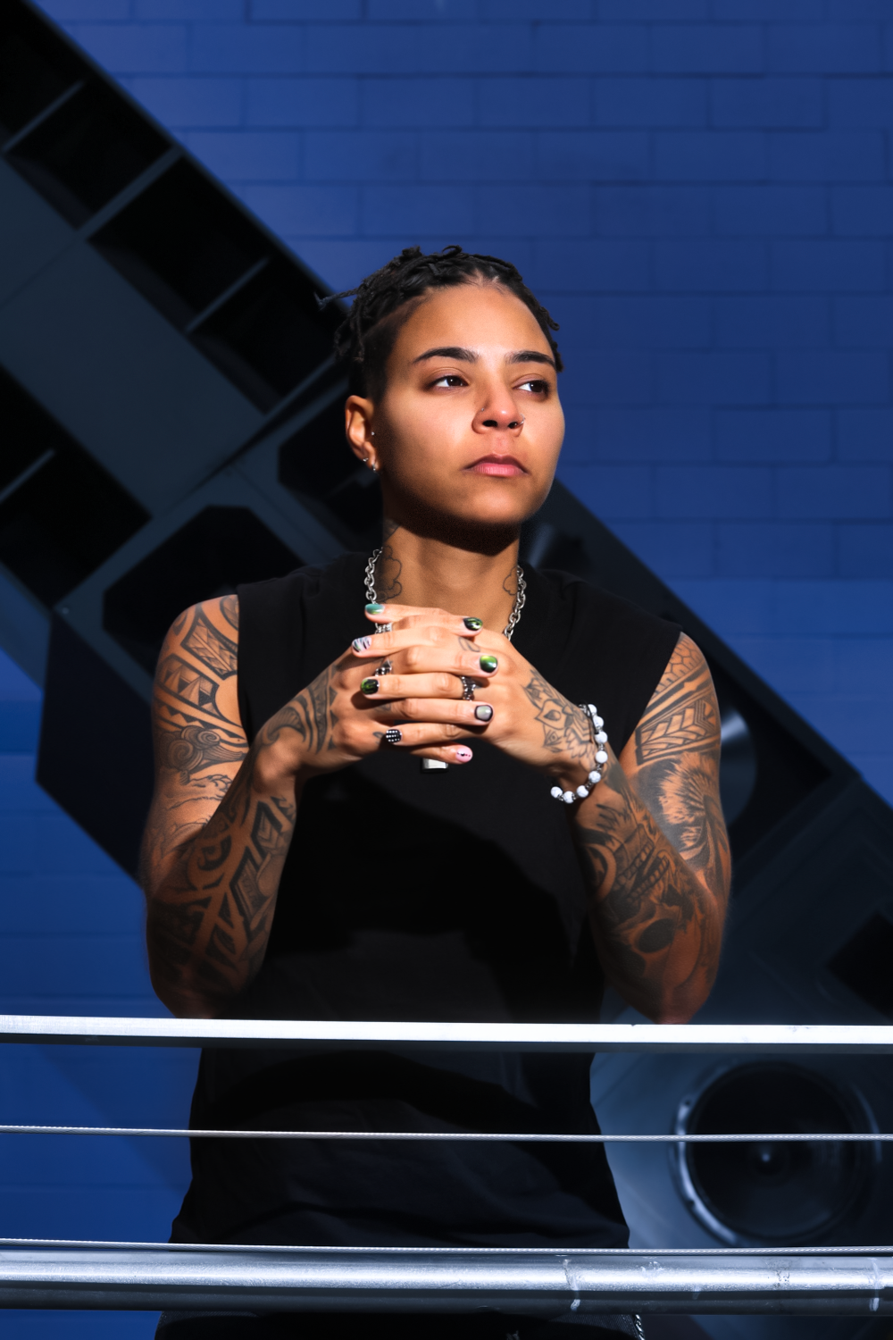 Artistic portrait series showing poses against a blue background with dramatic lighting and tribal tattoo artwork.