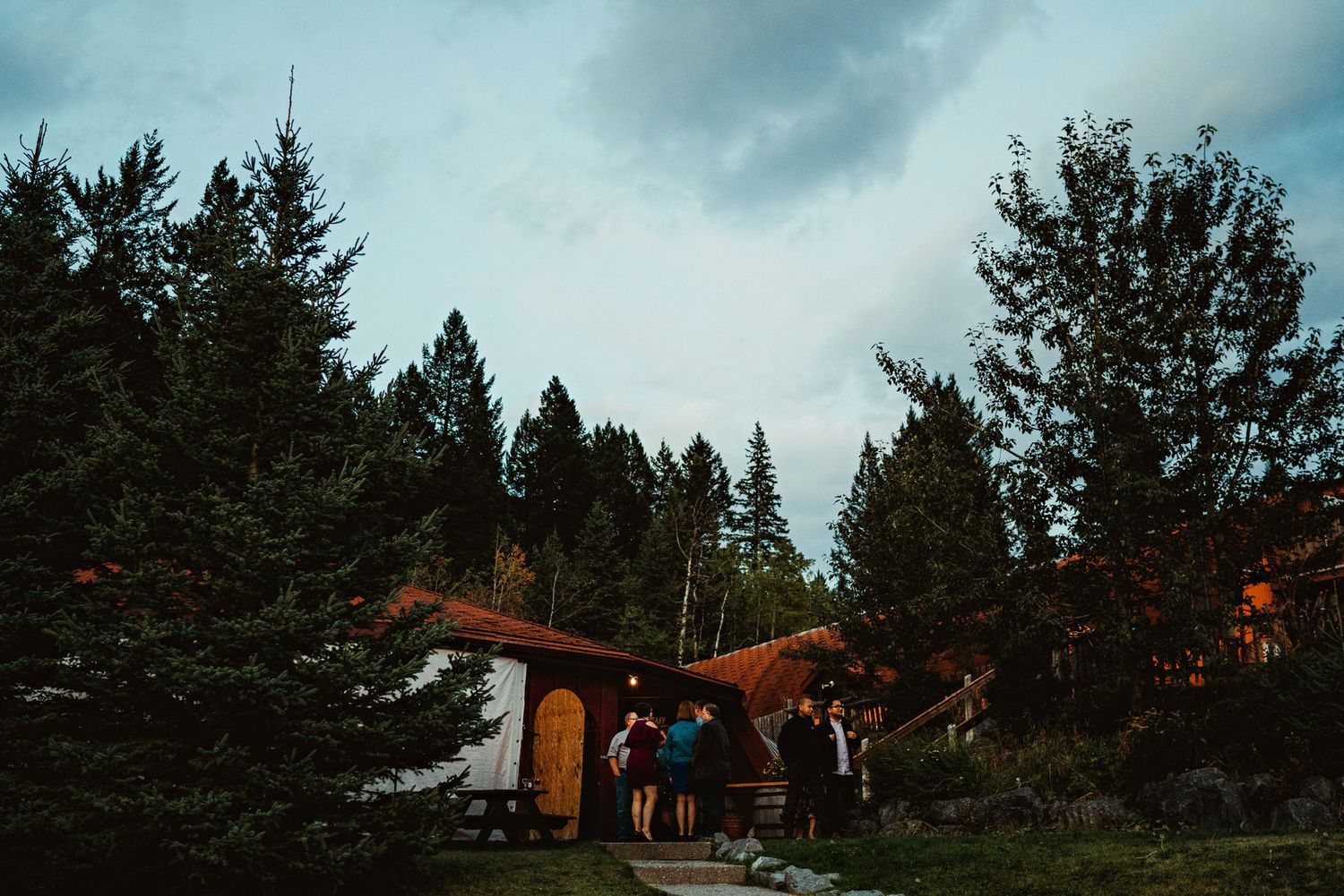Sunset view of mountain lodge cabins nestled among tall pine trees.