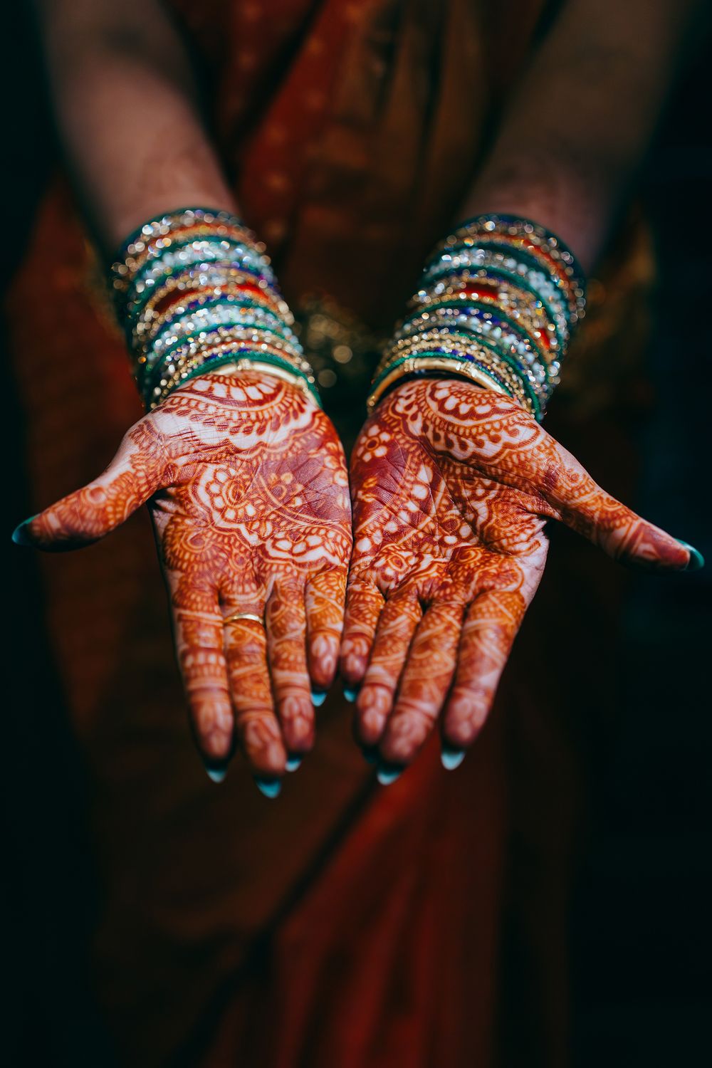 Decorative mehndi henna designs adorn hands wearing colorful bangles during a Telugu wedding in Dallas.