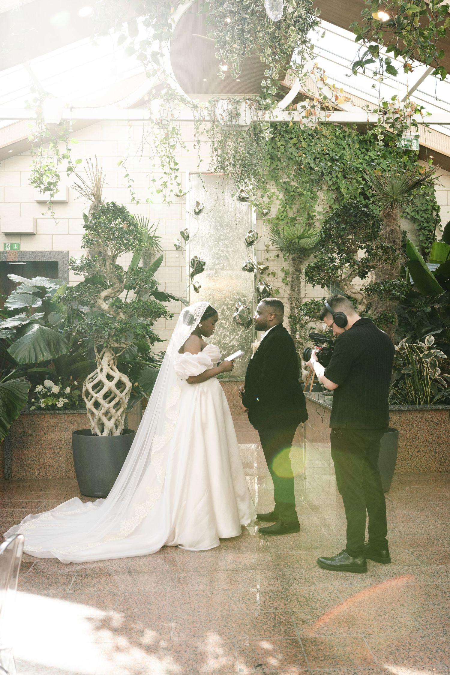 Wedding reception sequence showing guests in formal attire gathered in a plant-filled indoor venue.
