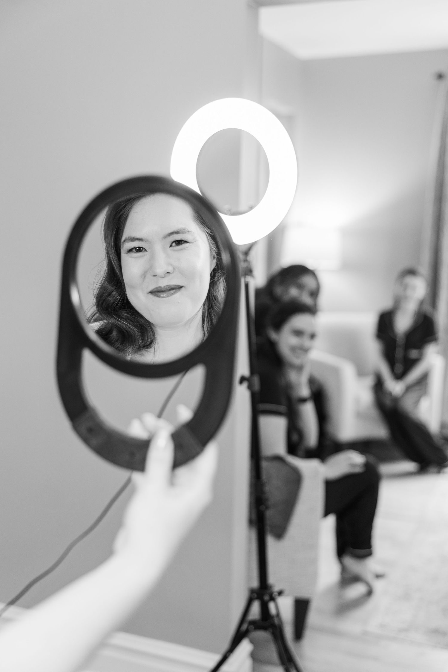A subject poses for a beauty photograph with a ring light casting a soft glow in black and white.