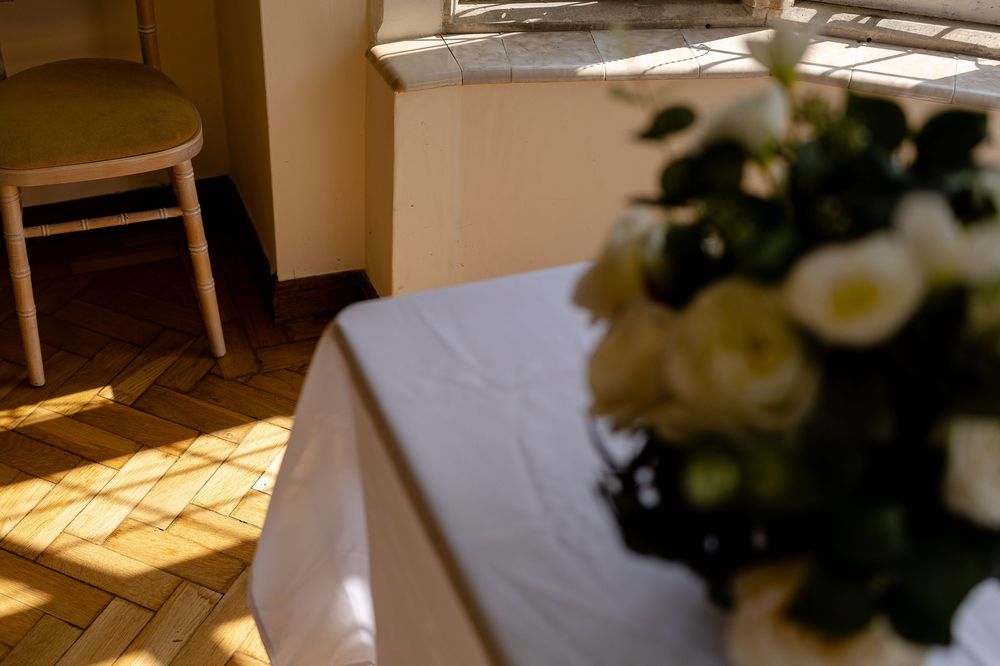 A warm sunbeam falls across a white tablecloth beside an elegant floral arrangement of white roses in natural light.