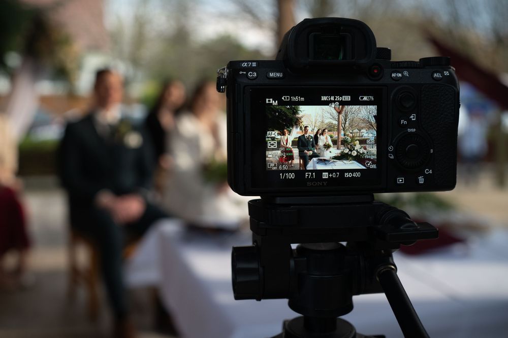 Close-up view of a camera LCD screen showing an event being filmed with blurred background at an outdoor gathering.