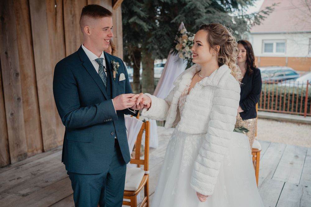A winter wedding couple shares a joyful moment during their ceremony on a rustic wooden porch.