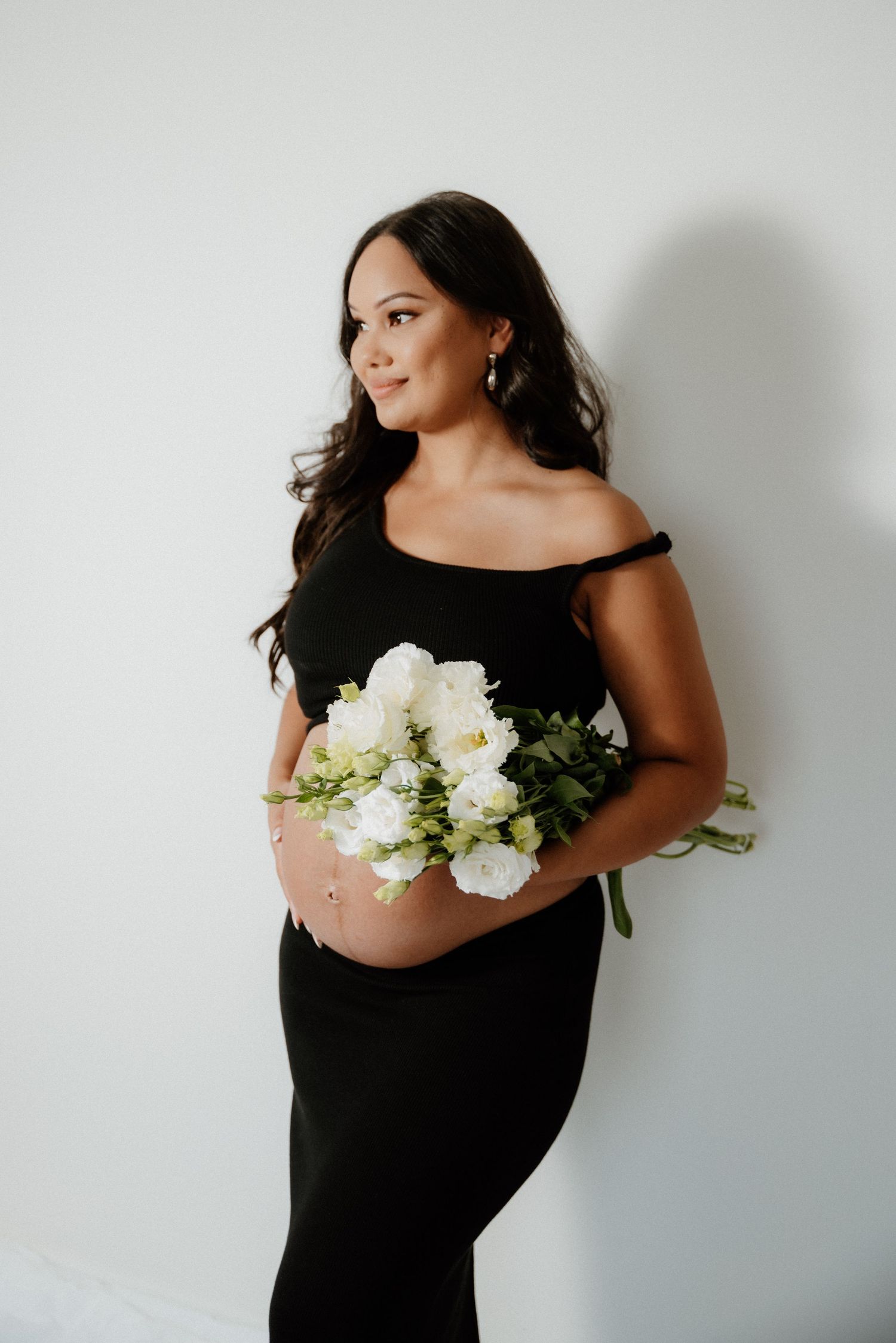 A romantic wedding moment captured outdoors with a flowing white dress and veil against lush green foliage.