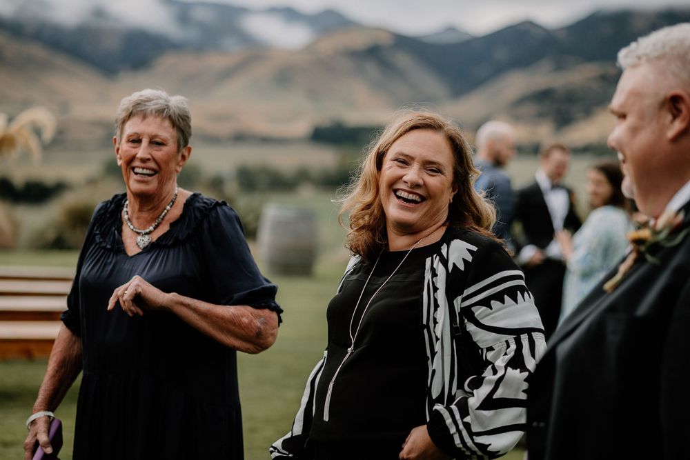 People share laughter and joy during an outdoor gathering with scenic mountains in the backdrop.