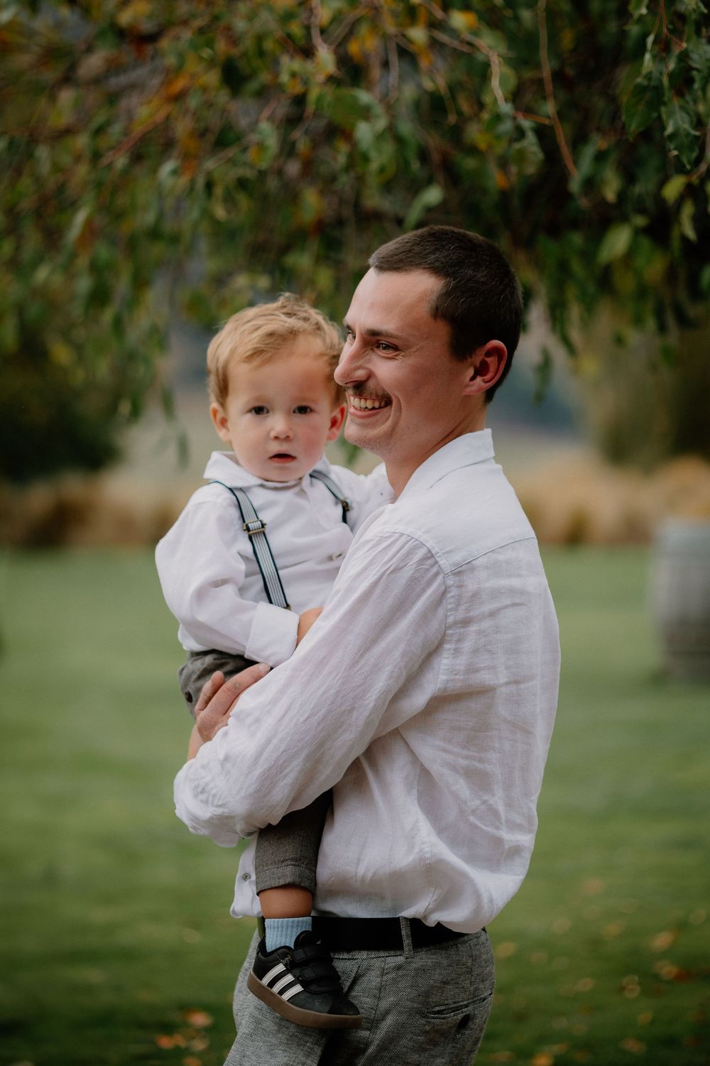 A touching outdoor portrait showing a loving embrace between a person in a white shirt and a small child in autumn.