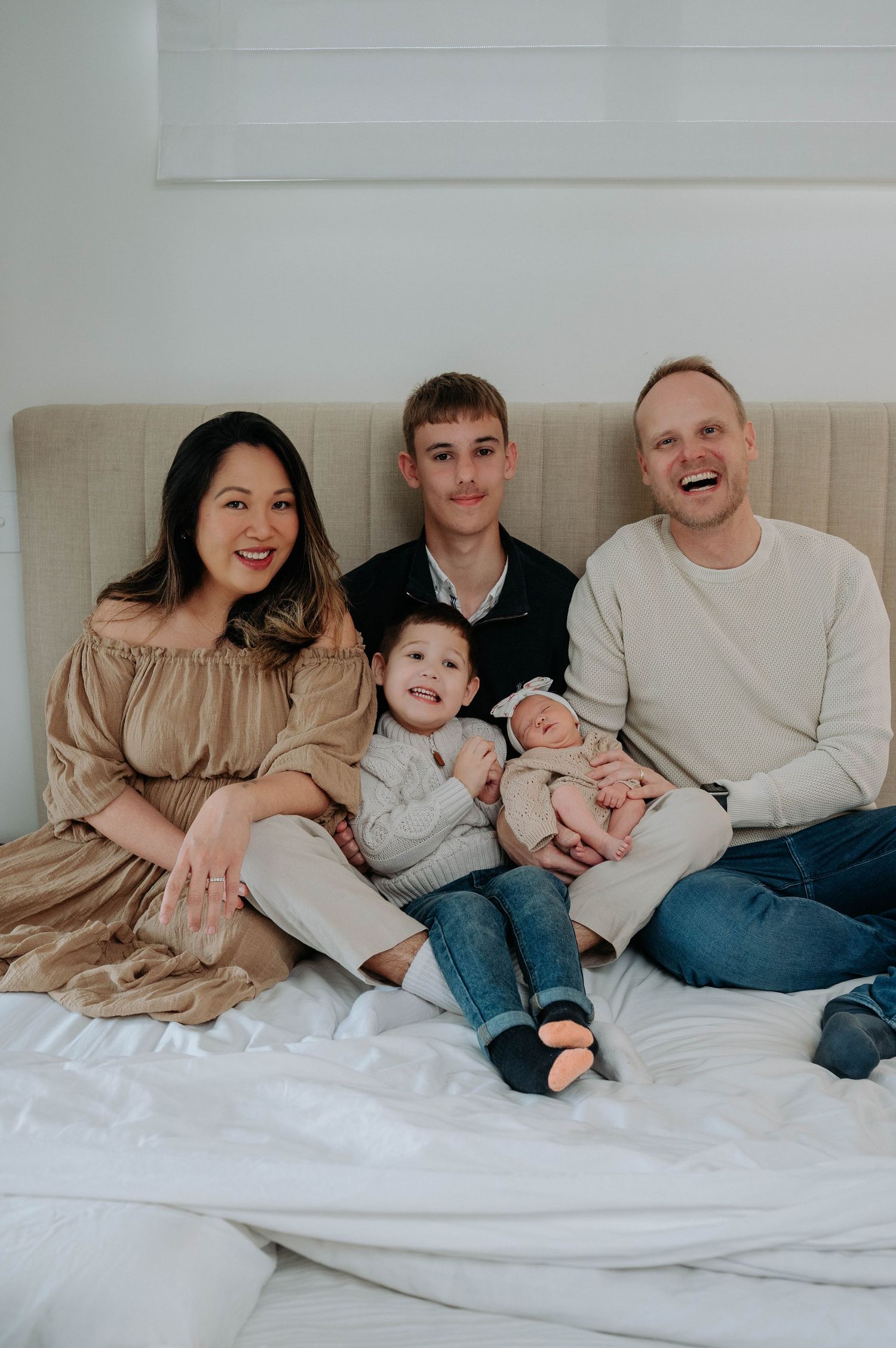 A series of five casual lifestyle photos showing a family cuddling and relaxing together on white bedding.