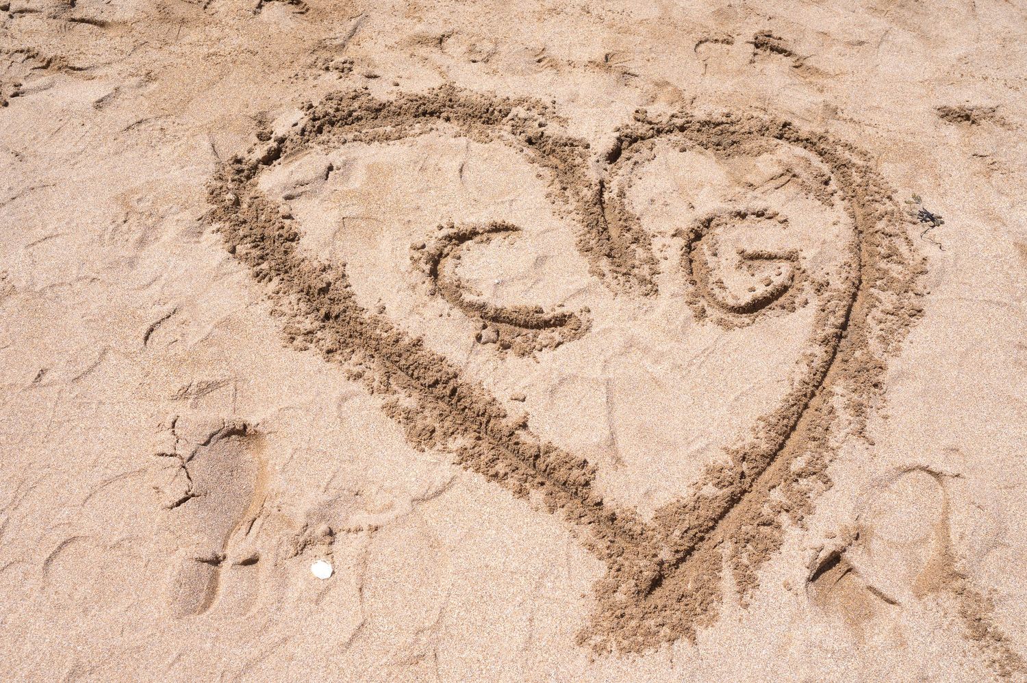 A romantic beach wedding ceremony takes place on a sandy shoreline with cloudy skies and ocean waves in the background