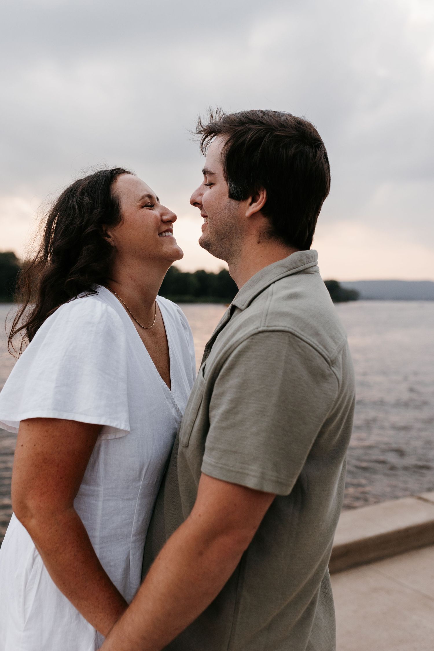 Heartfelt romantic photo sequence of a couple smiling and leaning in close together by the water at sunset.