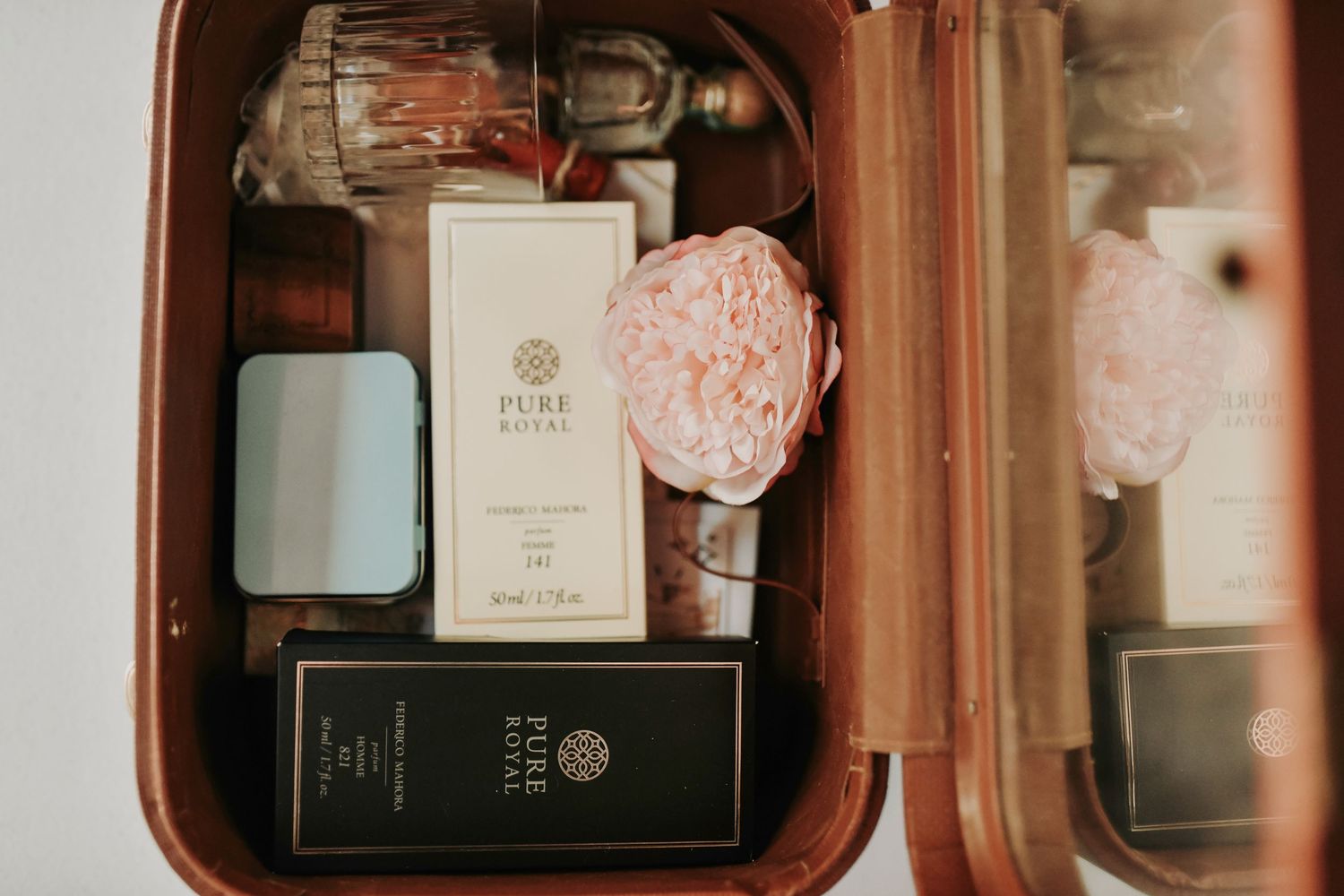 Flat lay of dusty blue invitation suite with wax seal and silk ribbon and other vintage details in a vintage suitcase