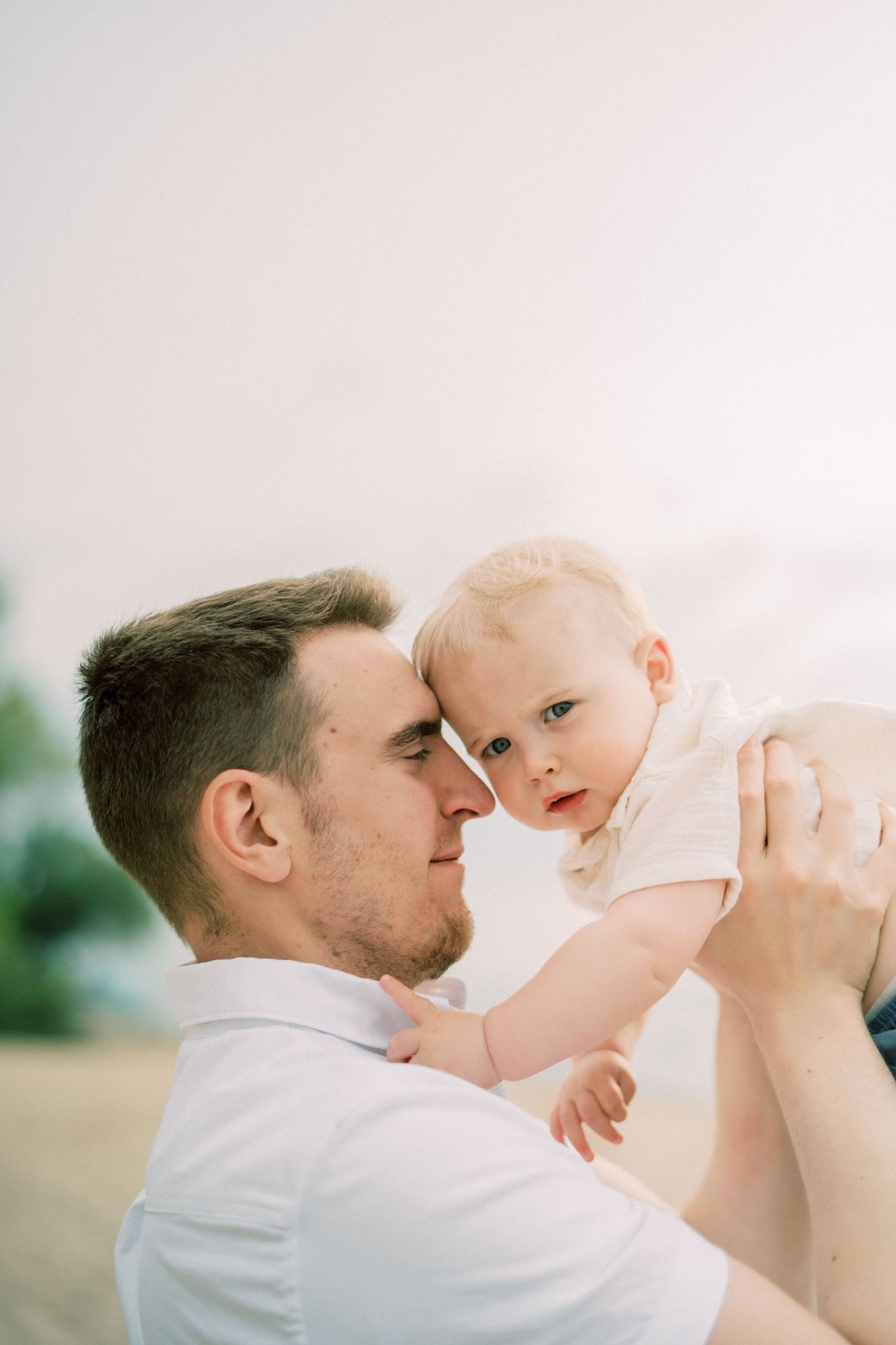 Series of tender moments between a parent and baby in white clothing against a light background.